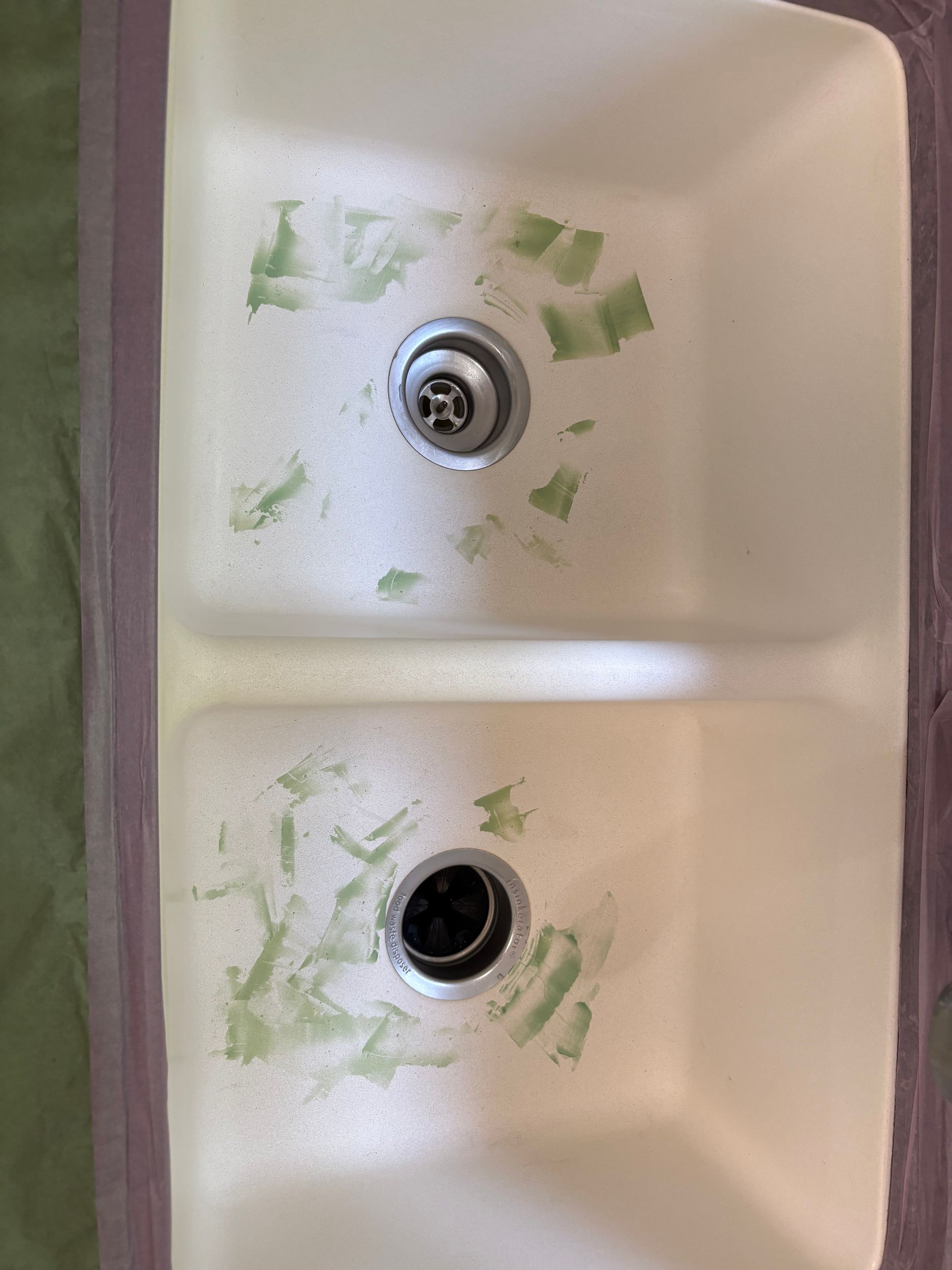 Double kitchen sink with green residue around the drains