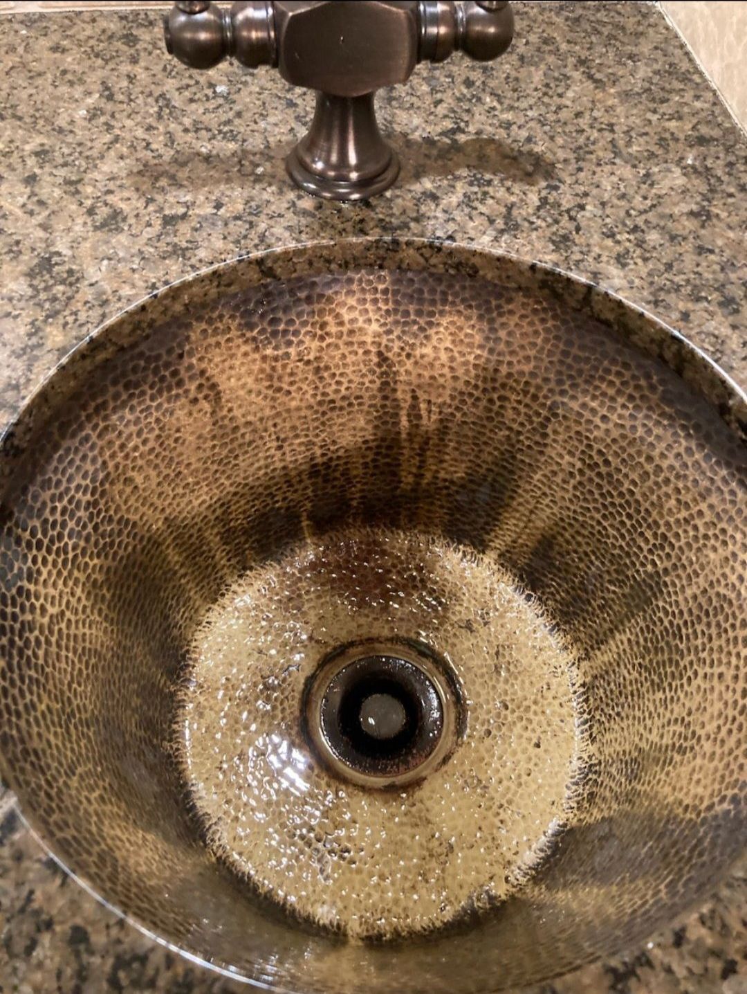 Brown textured bathroom sink with a central drain and chrome faucet on a speckled countertop