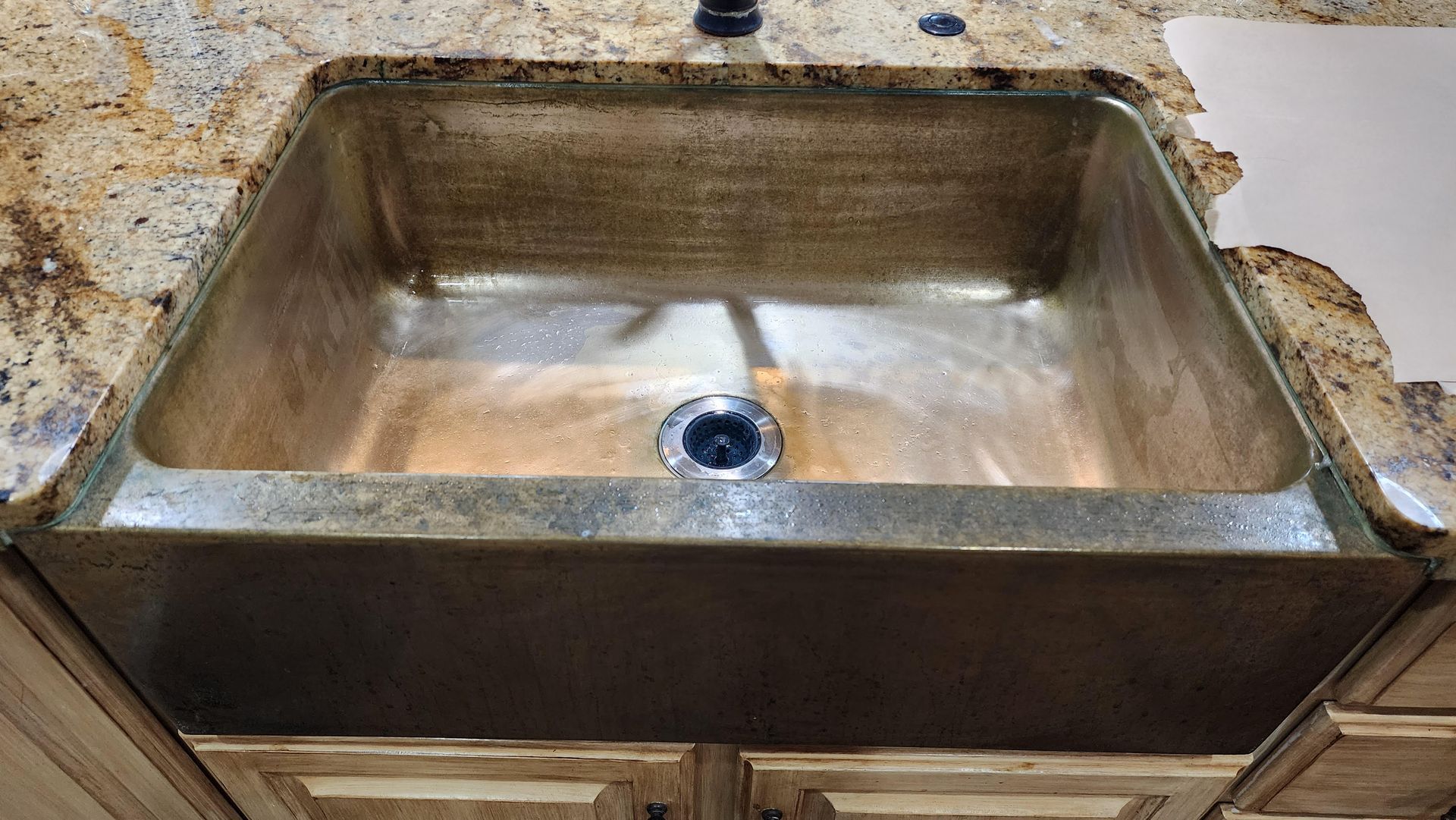 Rustic kitchen sink with a metal basin and granite countertop, viewed from above.