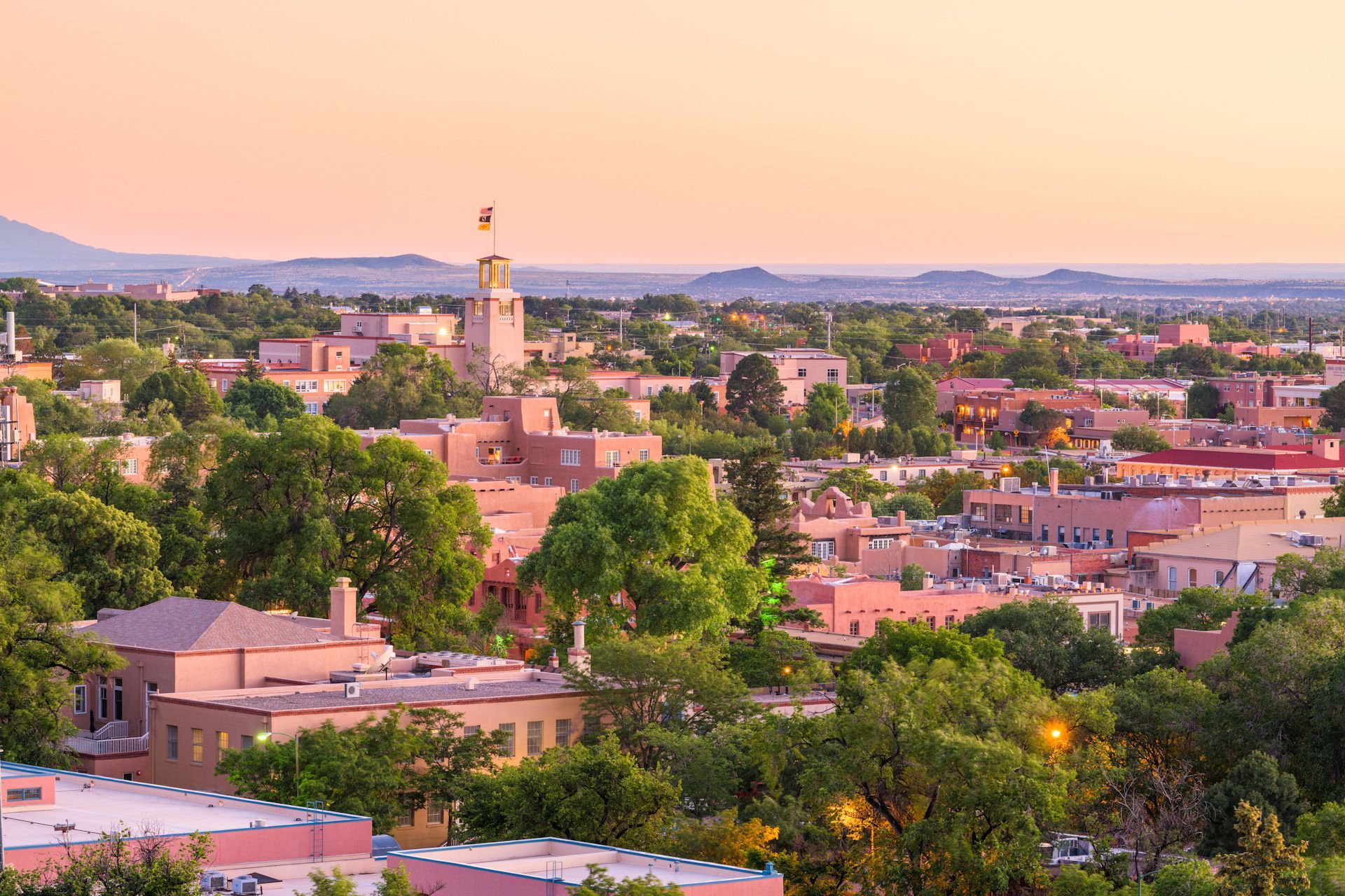 An aerial view of a city with trees and buildings at sunset.