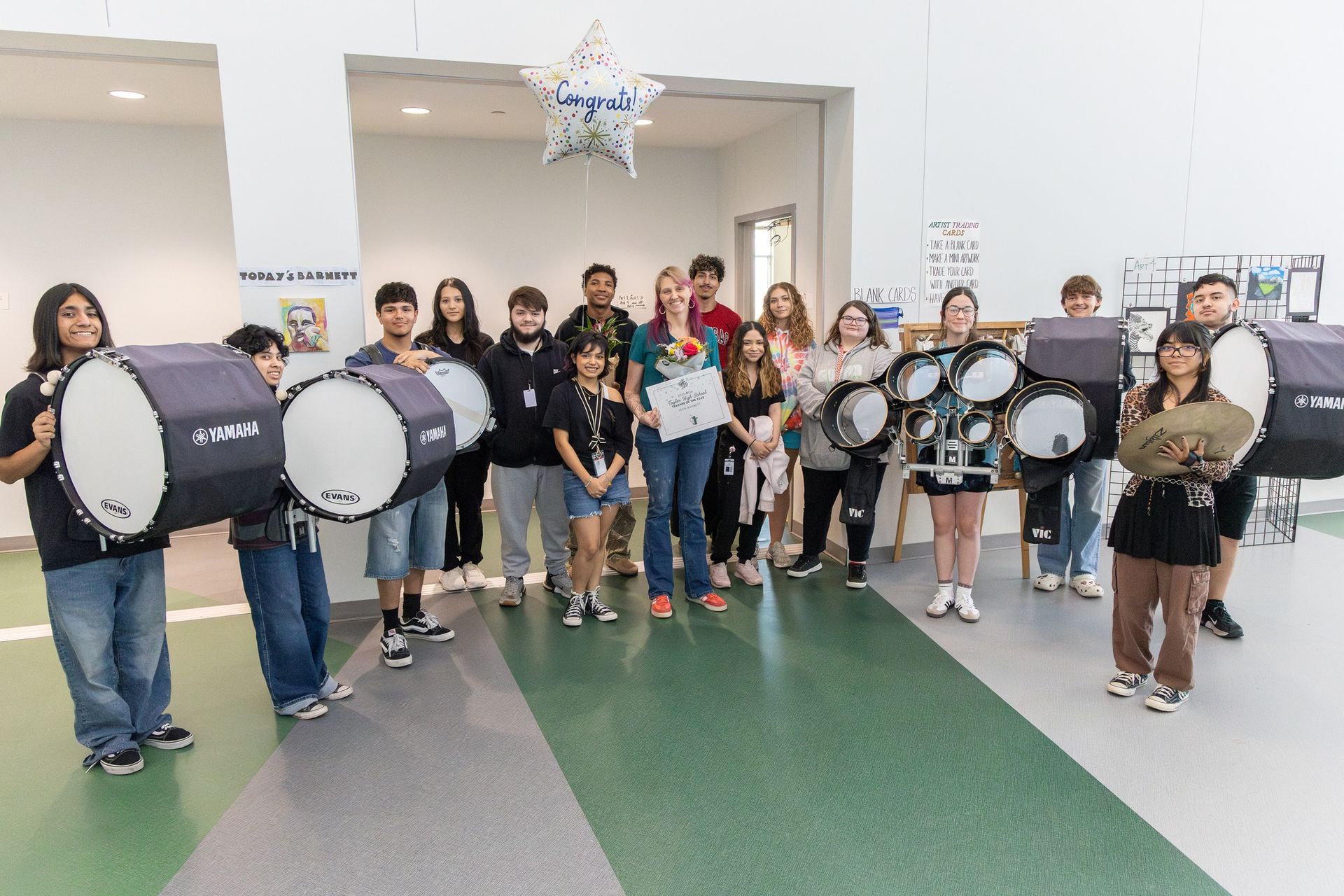 Group of students holding drums in a school hallway during a music performance