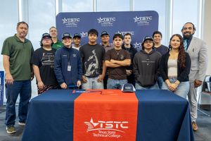 Group of people posing behind a red and blue ISTC table at an event backdrop