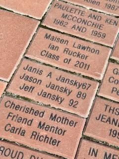 Engraved memorial bricks with names and messages in a brick walkway