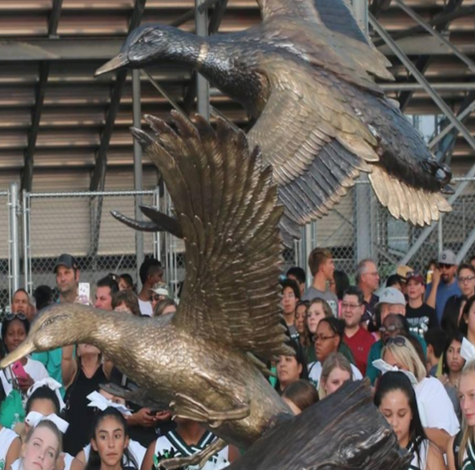 Bronze bird sculptures flying above a crowd in an indoor atrium