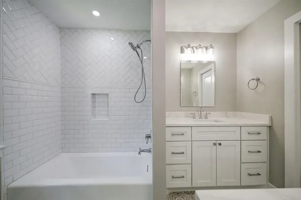 Bright white bathroom with bathtub shower and vanity mirror under lights