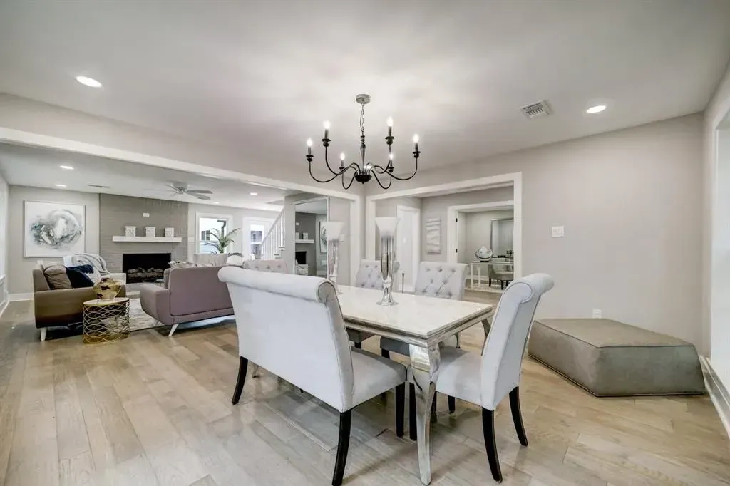 Elegant open-plan dining and living room with white chairs, chandelier, and beige decor