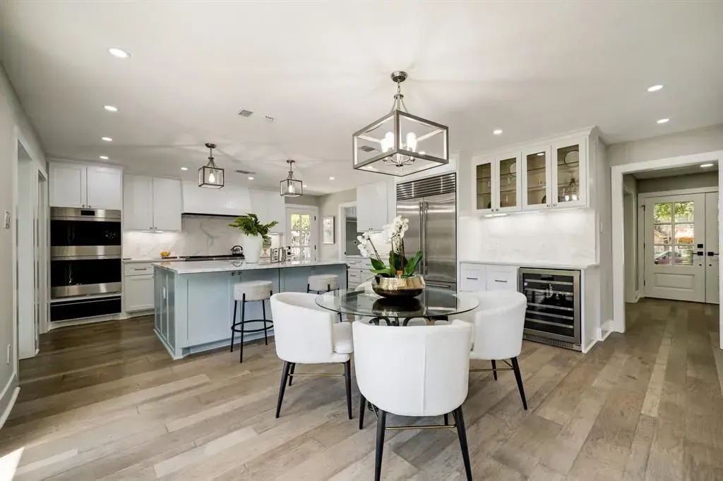 Bright open kitchen and dining area with white cabinetry, island, and light wood floors