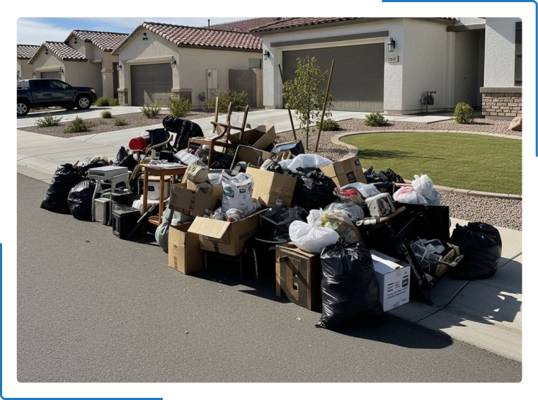 A large pile of household trash, boxes, and discarded items sits on a suburban street curb for bulk waste collection.