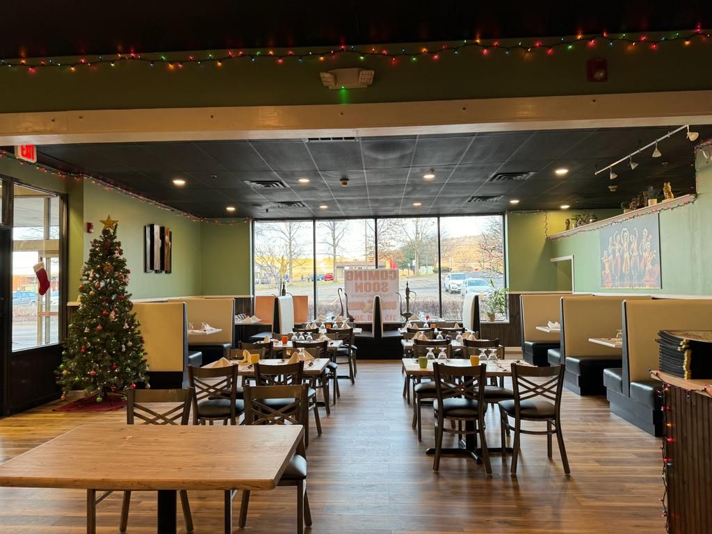 Restaurant interior with tables, booths, and a Christmas tree near the window.