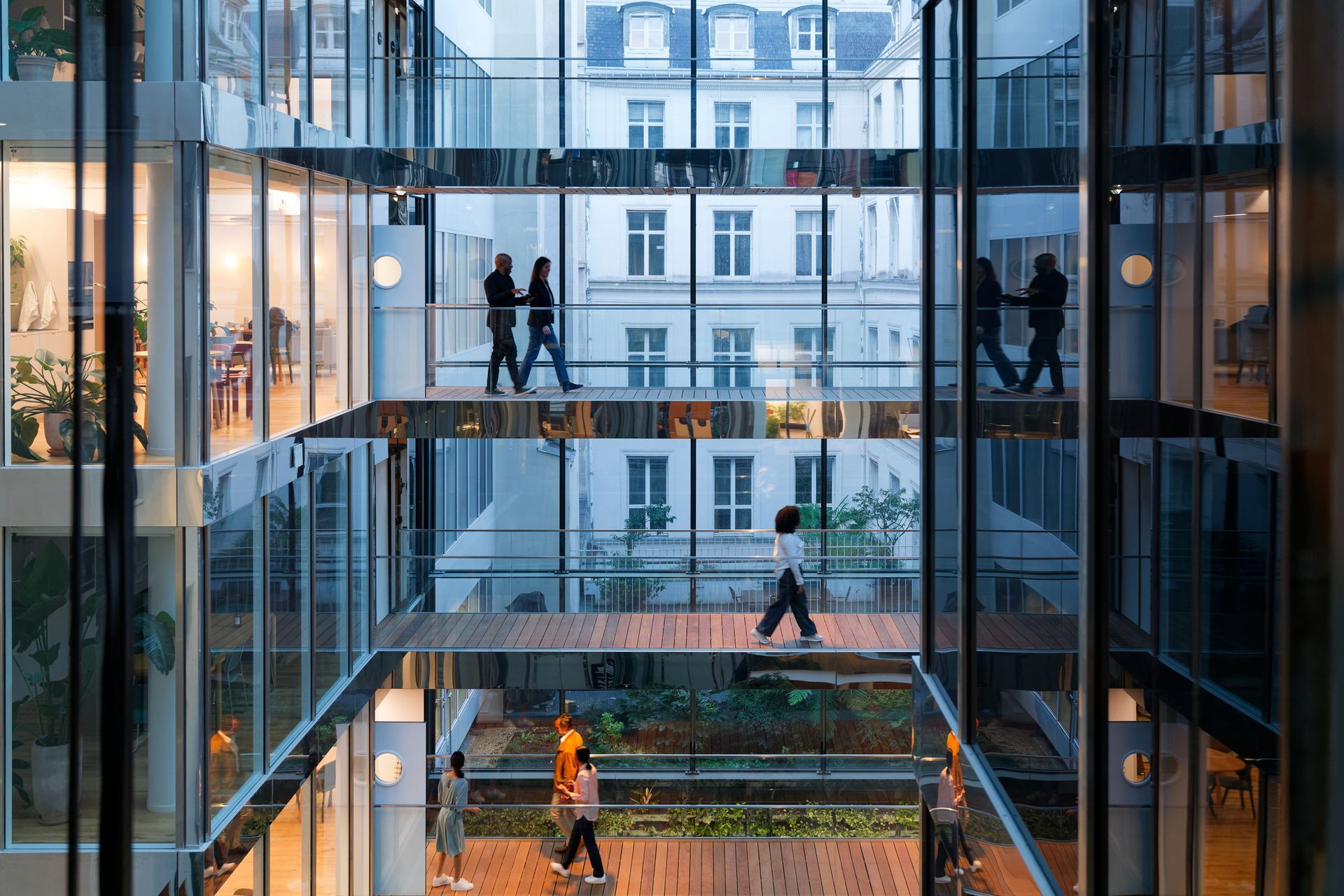 A group of people are walking through a glass building.