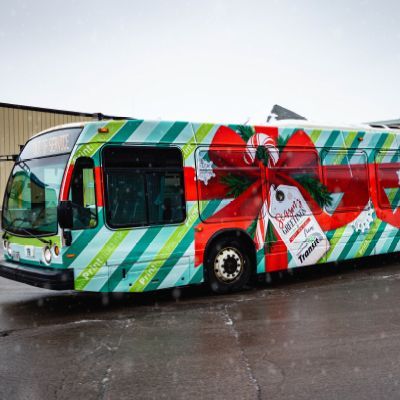 A bus with a christmas theme is parked in a parking lot