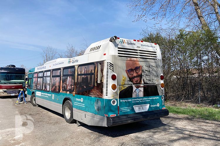 A bus with a picture of a man on the back is parked in a parking lot.