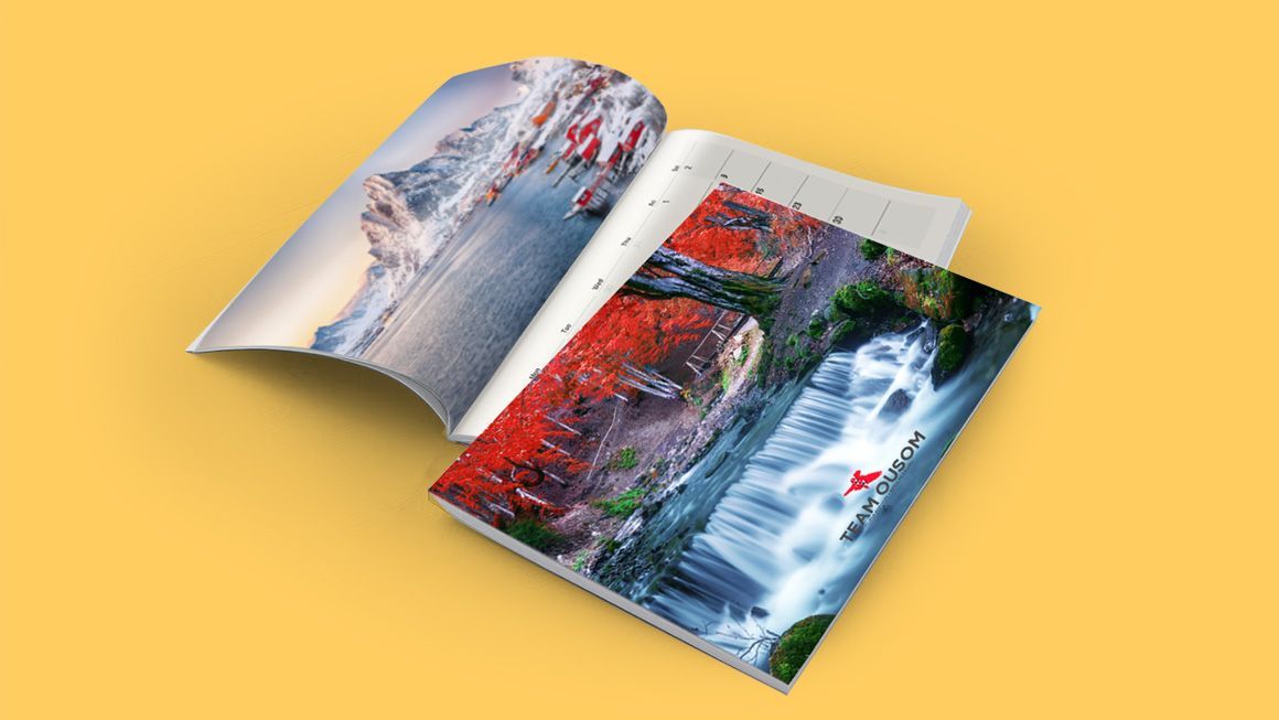 A magazine is open to a page with a waterfall and mountains on it.