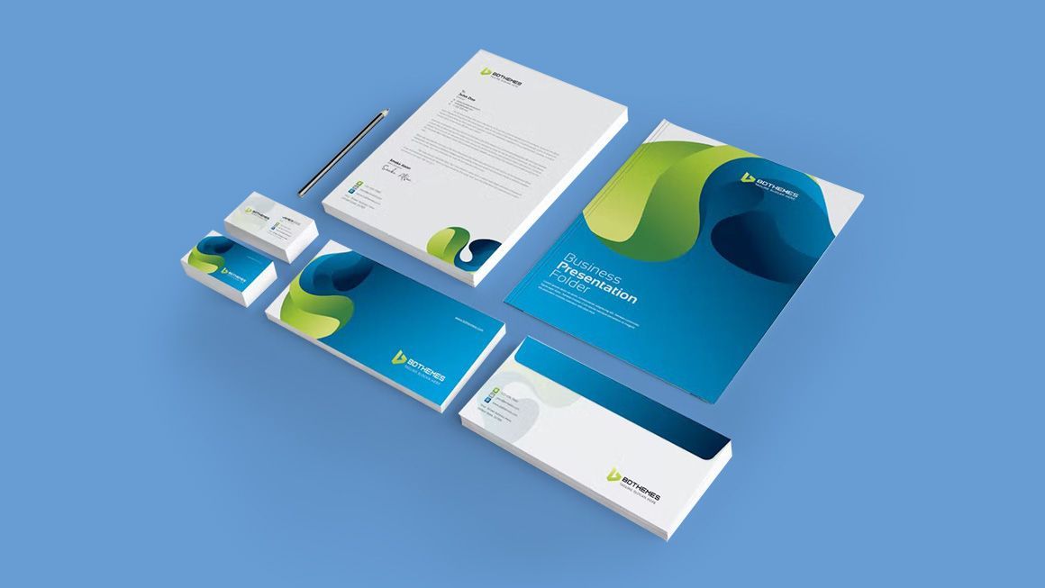 A set of business cards , envelopes , and a notebook on a blue background.