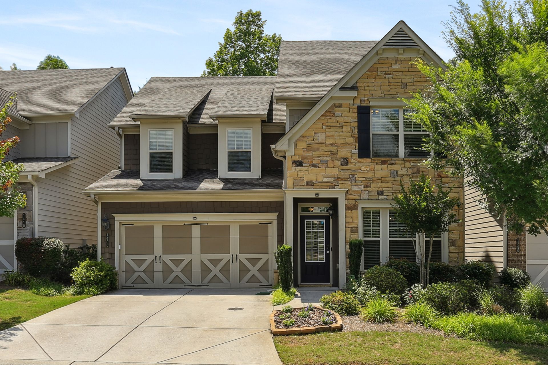 Two-story suburban house with stone facade, double garage, and front lawn