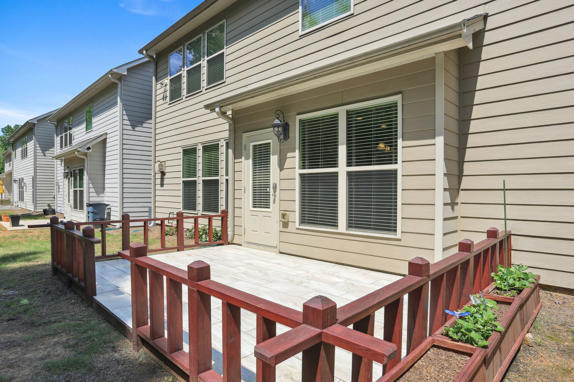 Row of beige townhomes with red railings and a small concrete patio in front