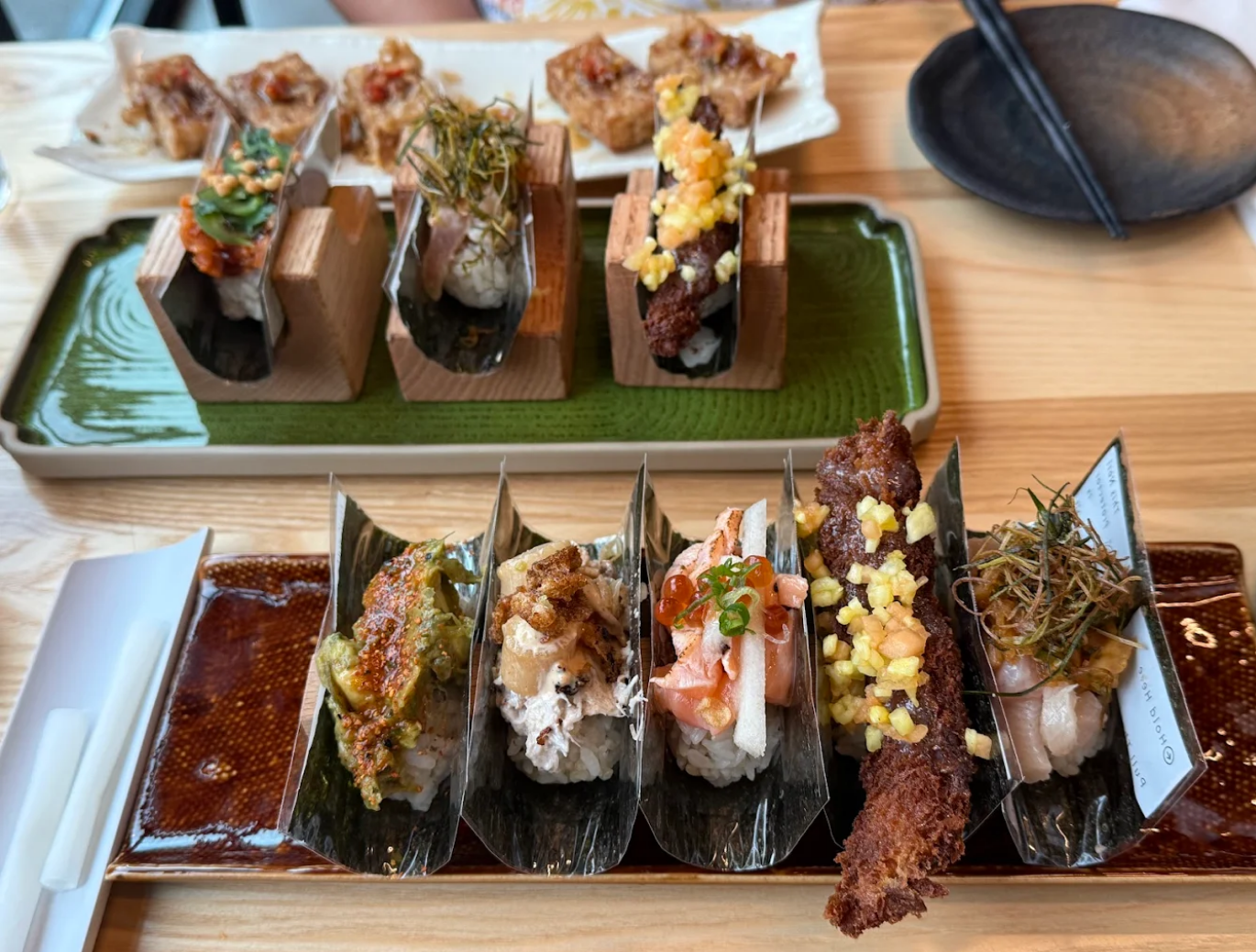 Sushi tacos in various presentations on a wooden table, including tempura.