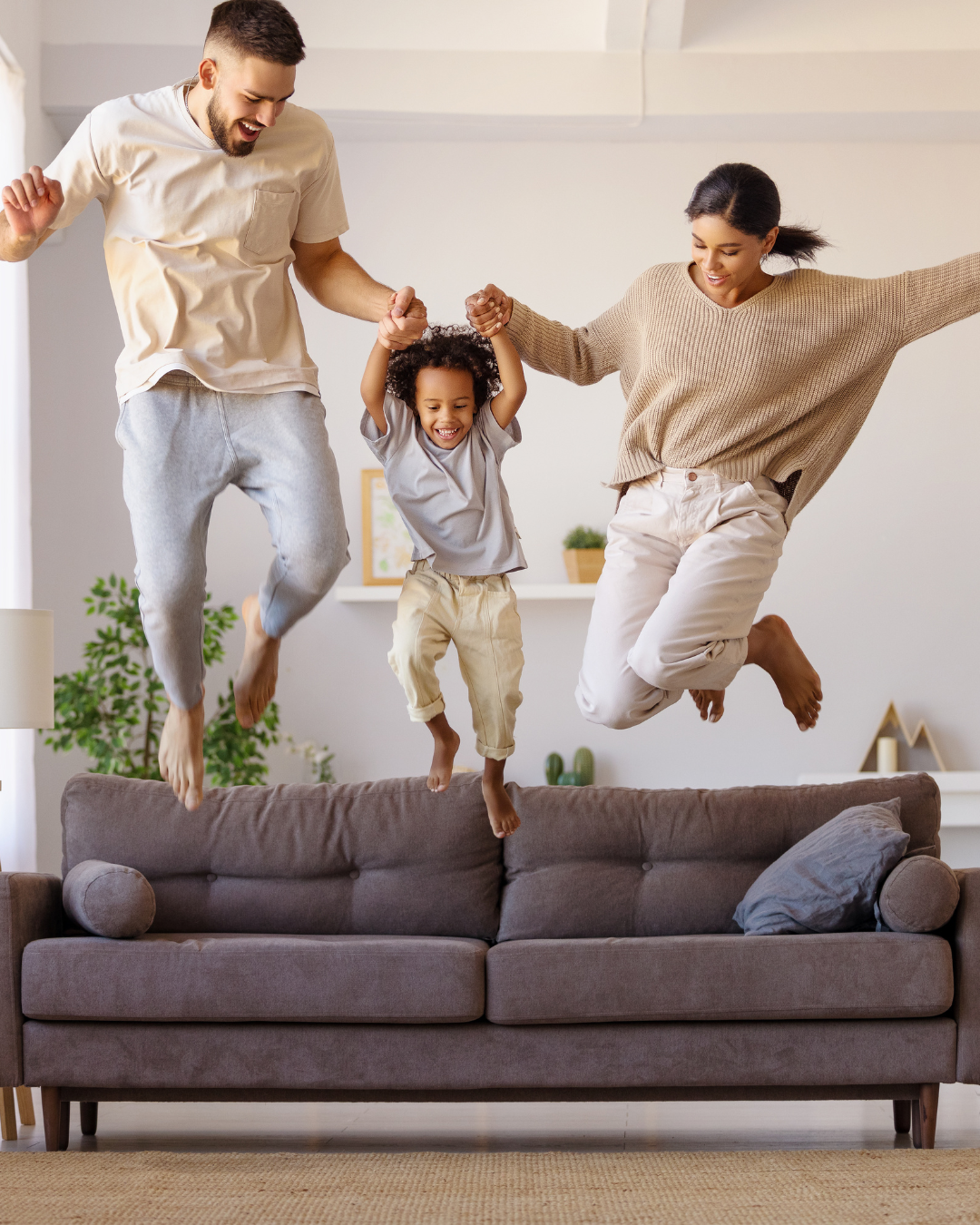 Family jumping joyfully on a sofa indoors.