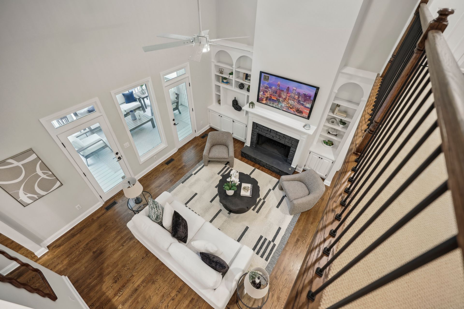 High-angle view of a living room with a white sofa, rug, fireplace, and two armchairs.