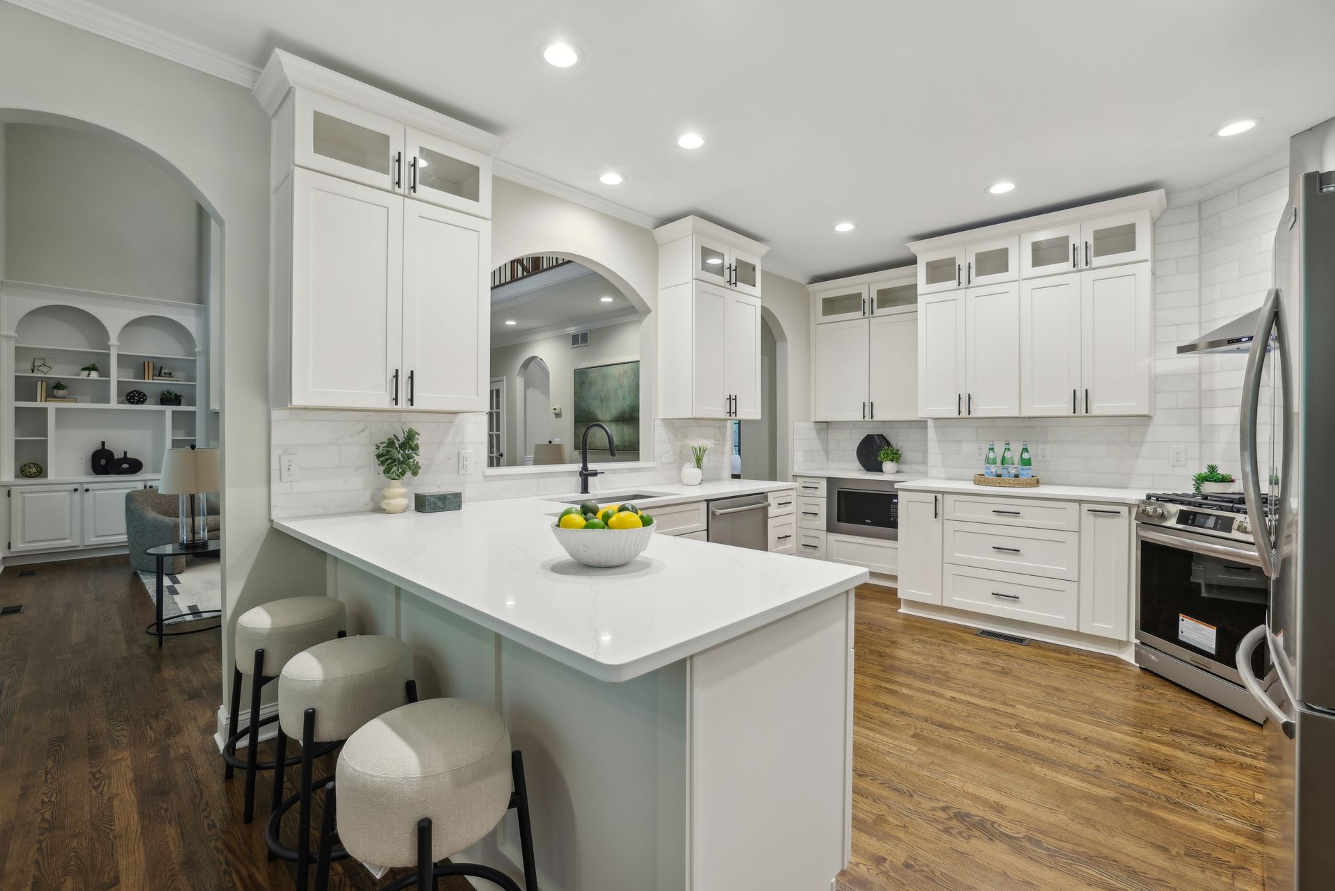 White kitchen with island, cabinets, and appliances on hardwood floors.