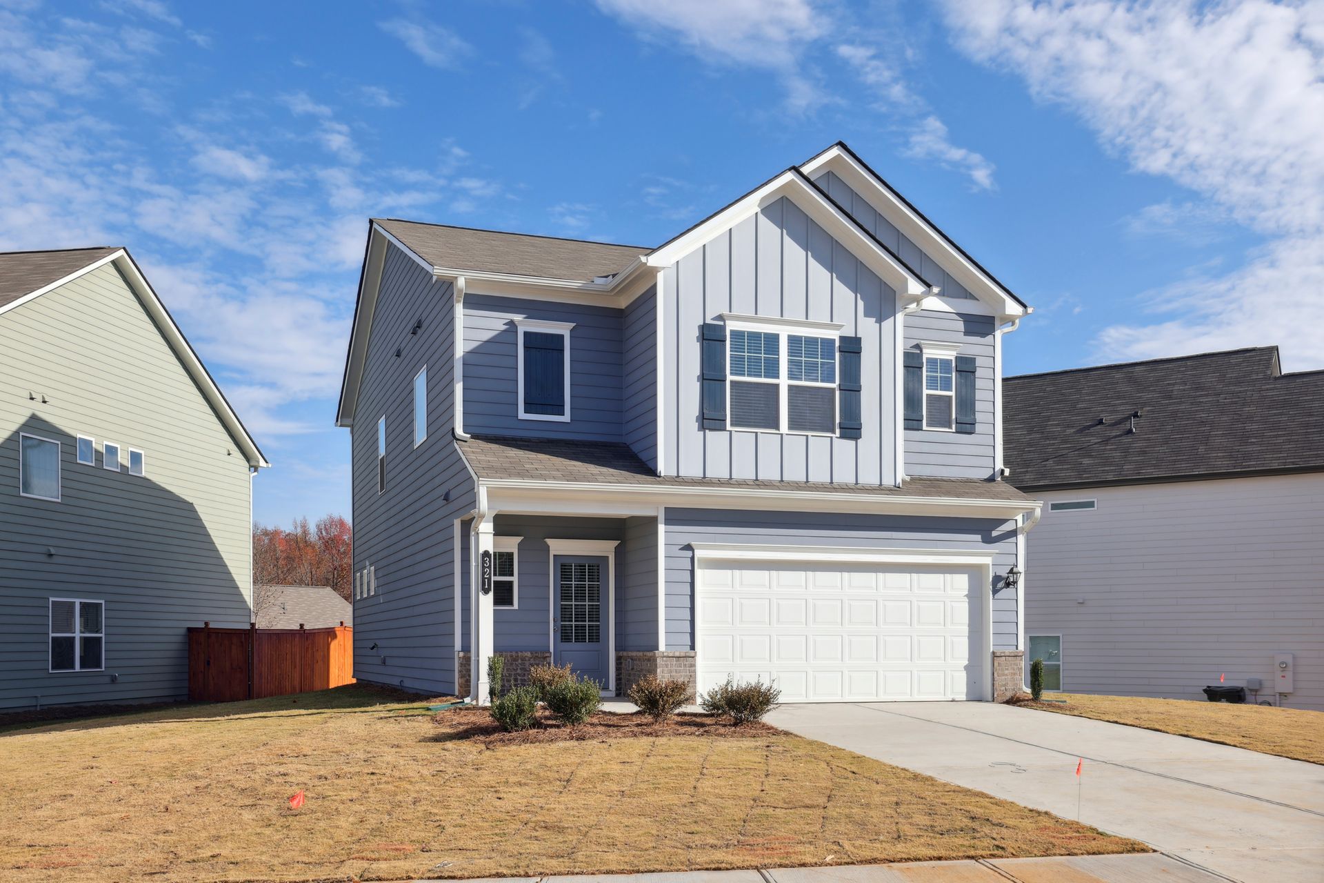 Two-story suburban house with blue siding, white trim, and a two-car garage on a sunny day