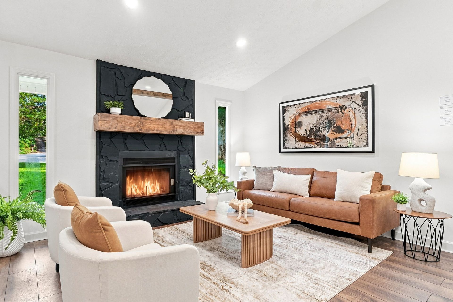 Bright modern living room with a black fireplace, tan sofa, white armchair, and wooden coffee table