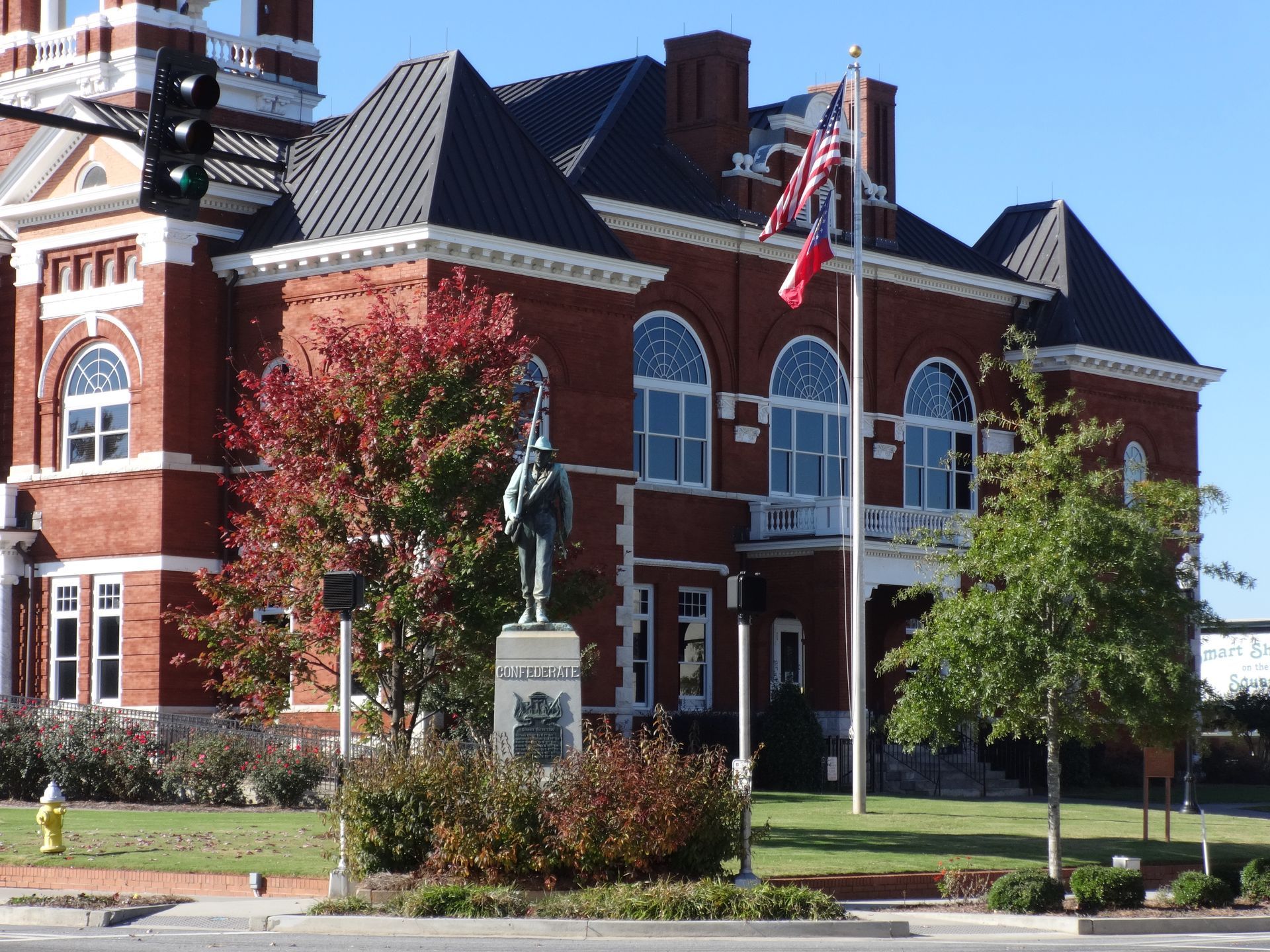 Brick courthouse with a statue in front; American and state flags fly.