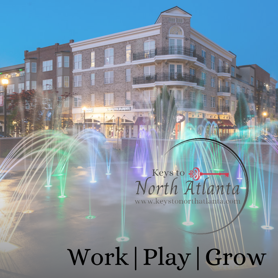 Colorful fountain in front of multi-story brick building at dusk. “Keys to North Atlanta” logo. Work | Play | Grow.