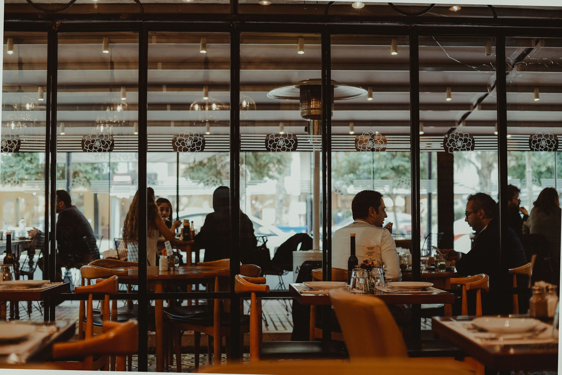 People seated at tables in a modern cafe with large windows and warm lighting