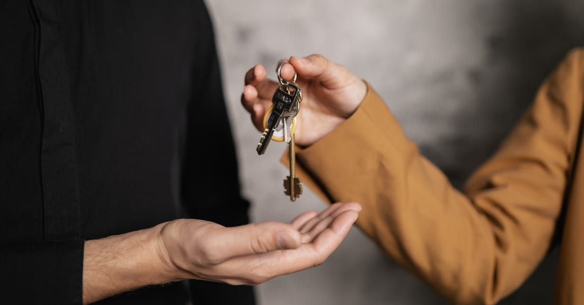 Person in brown jacket handing keys to another person in black shirt.