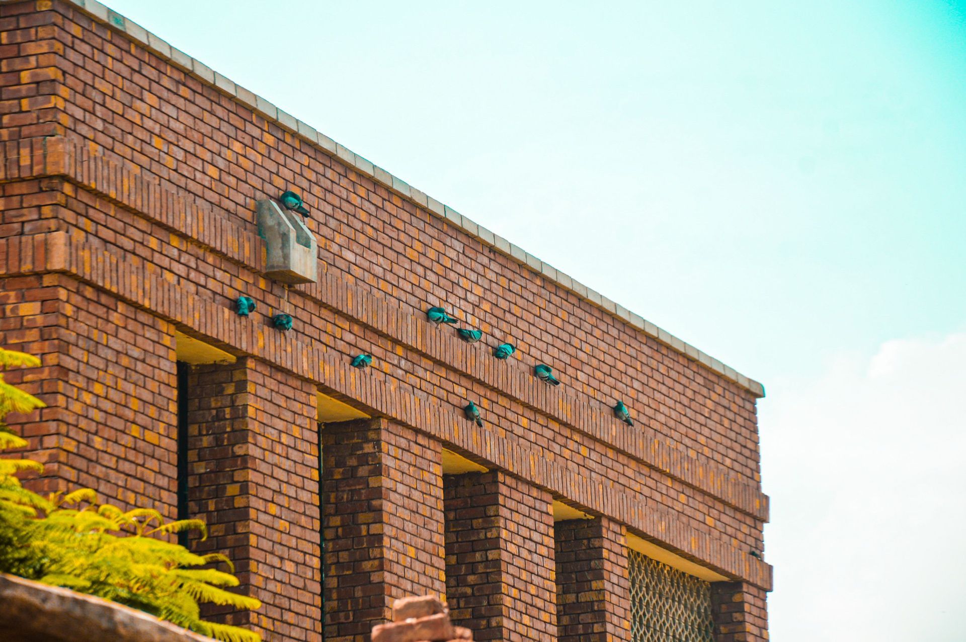 Brick building facade with arched windows and a vintage lantern under a clear sky