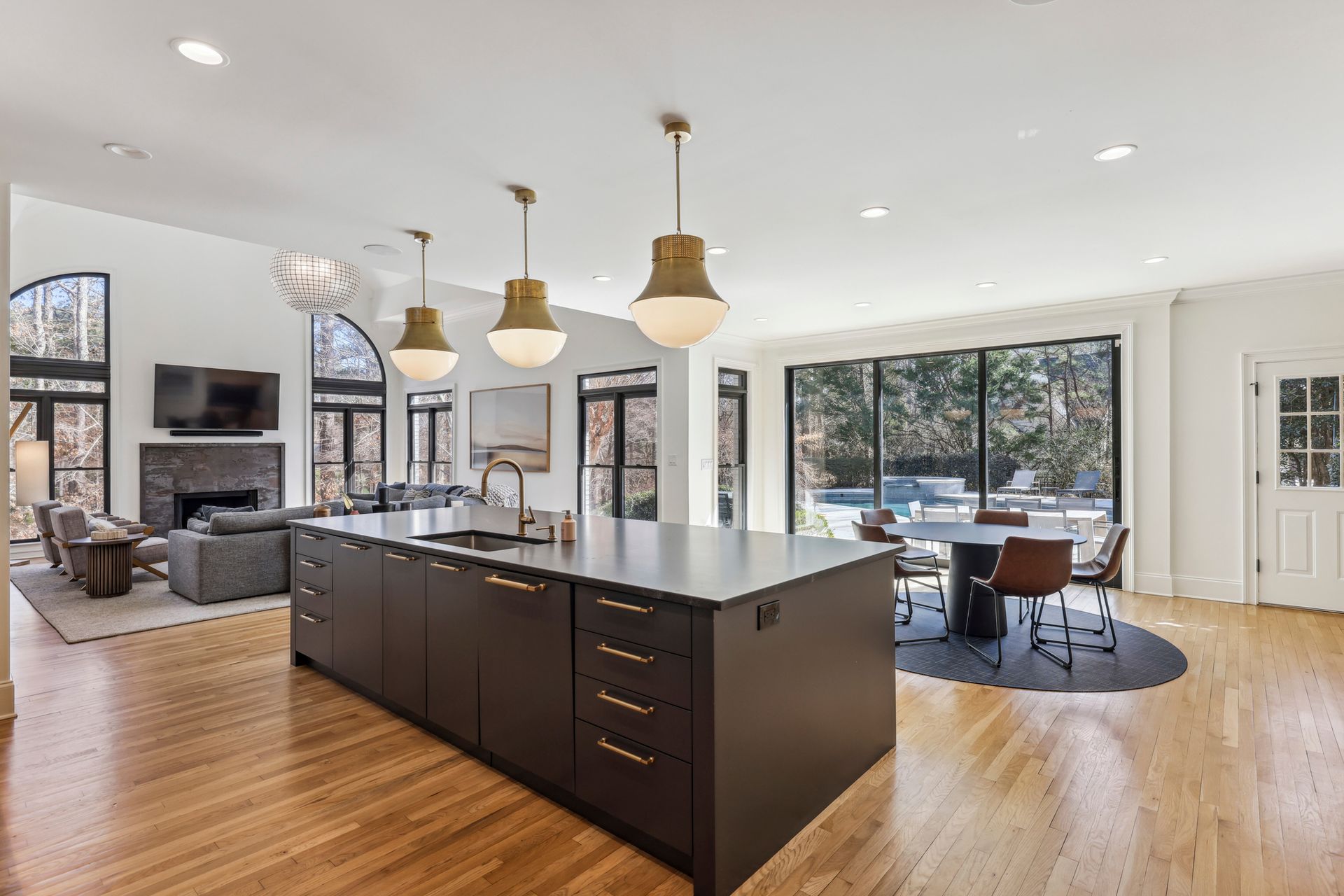 Open-plan kitchen with large island, pendant lights, and living area with fireplace and large windows.