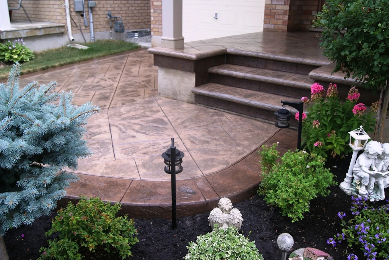 A concrete patio with stairs and flowers in front of a house.