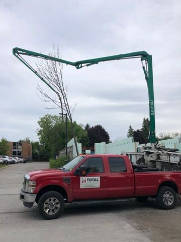 A red truck with a green crane on the back is parked in a parking lot.