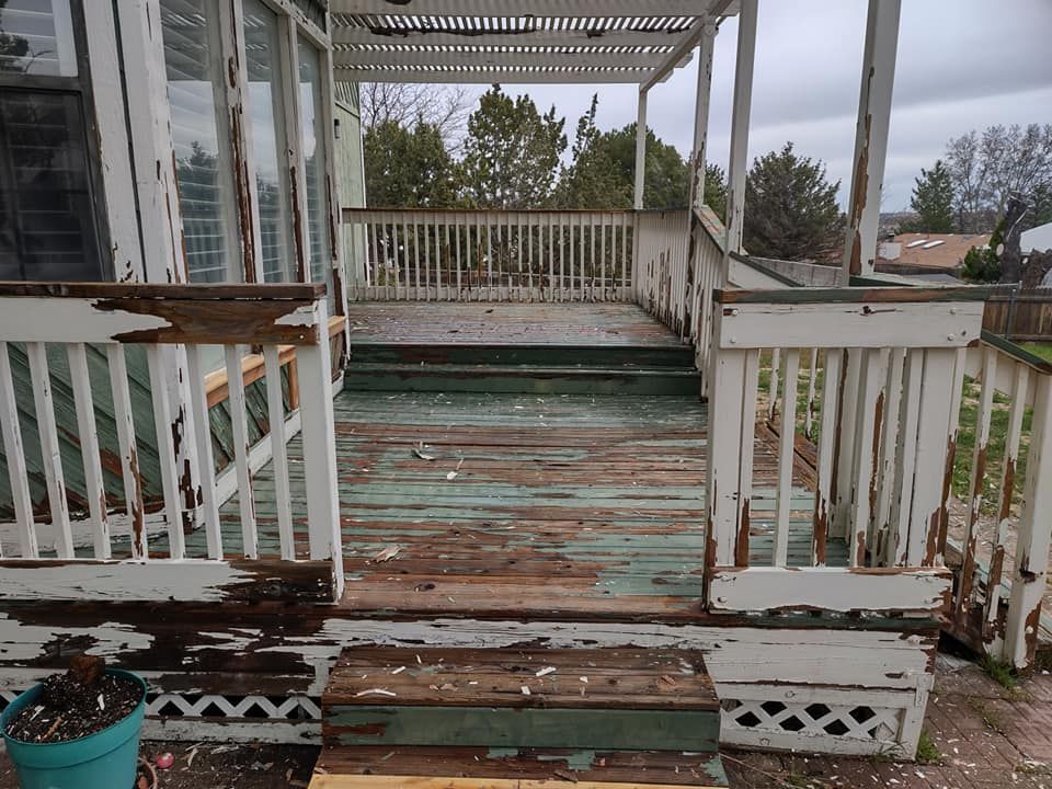 A old worn out wooden deck with a white railing and stairs.