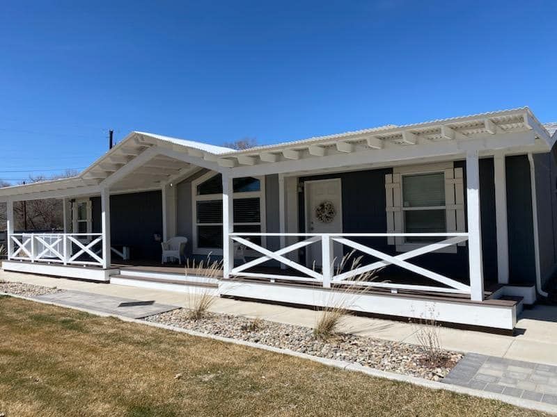A black house with a white porch against a blue sky, freshly painted with residential exterior services.