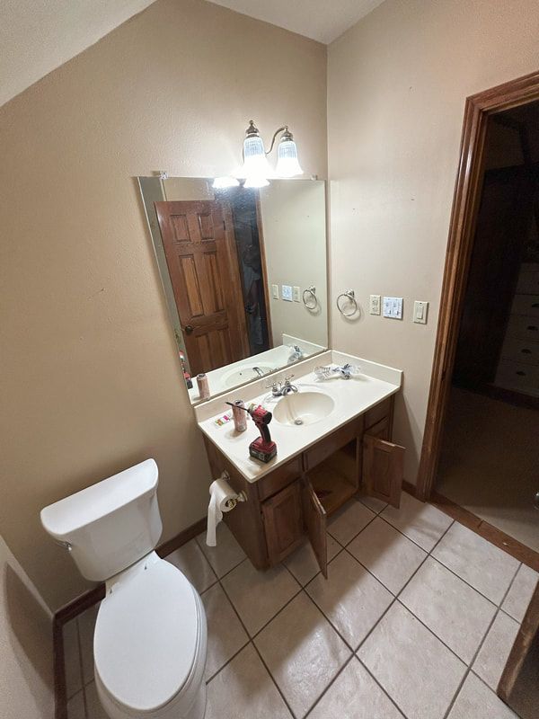 A bathroom with a toilet , sink and mirror.