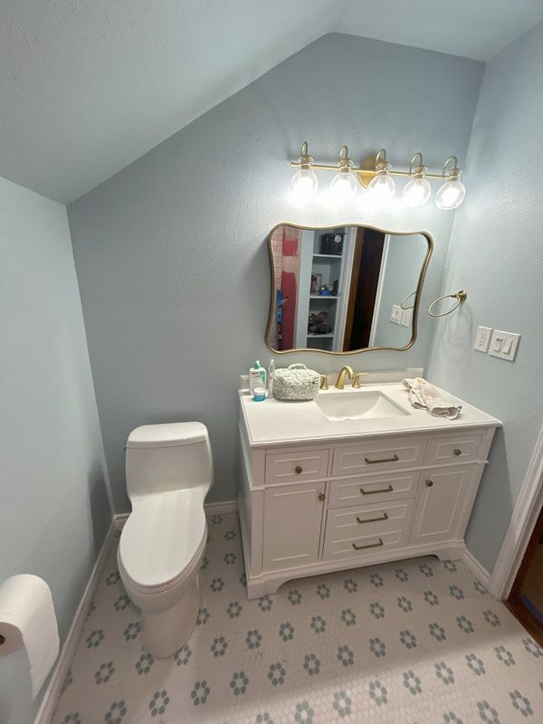A bathroom with a toilet , sink and mirror.