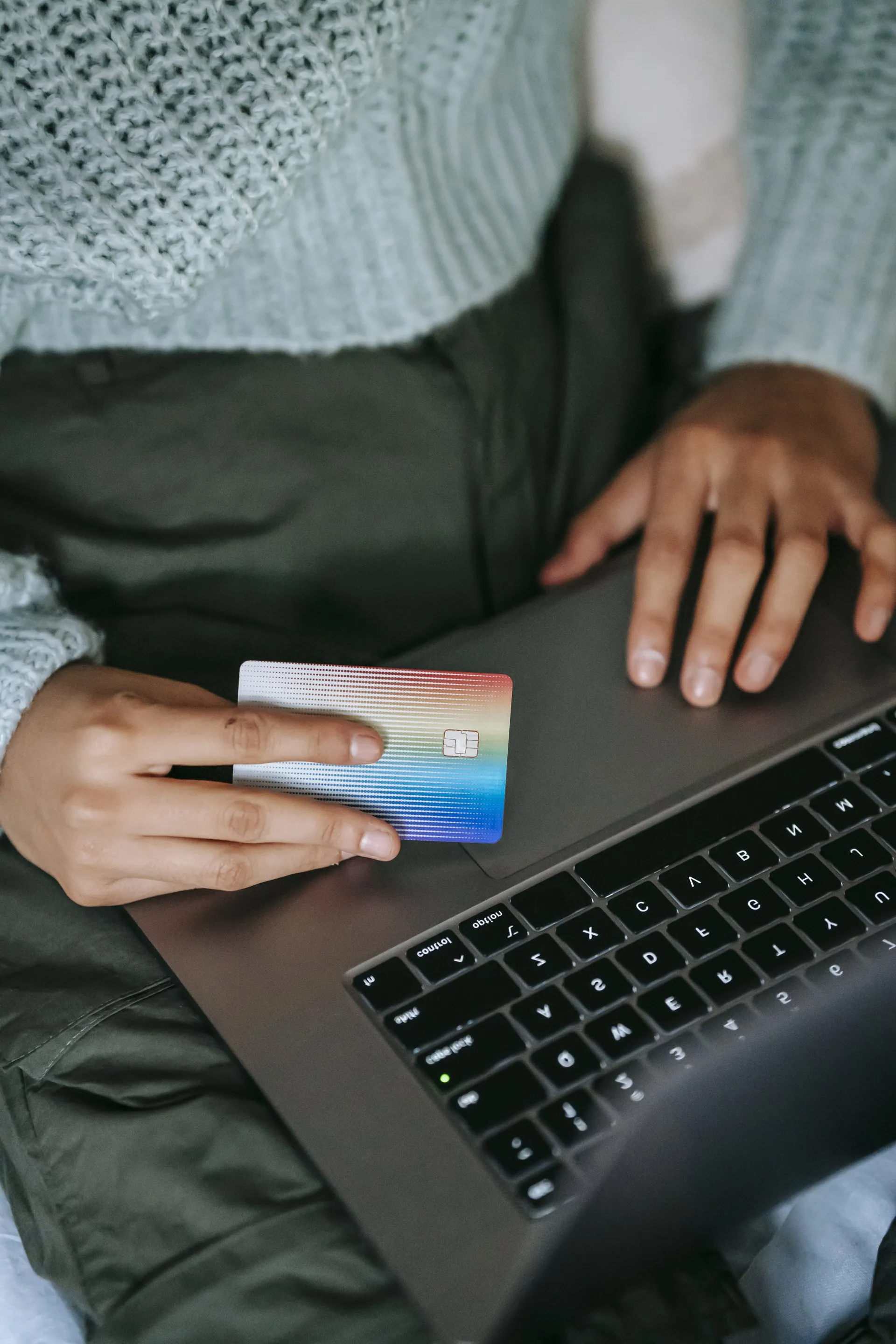 Person with credit card typing on a laptop, online shopping.