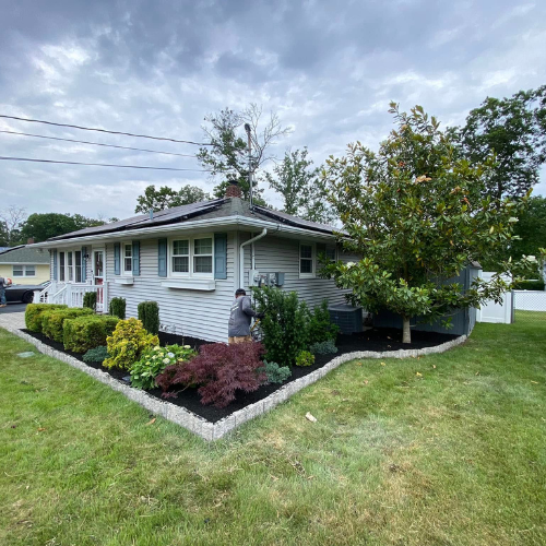 Ranch-style house with light blue siding and well-maintained landscaping under a cloudy sky.