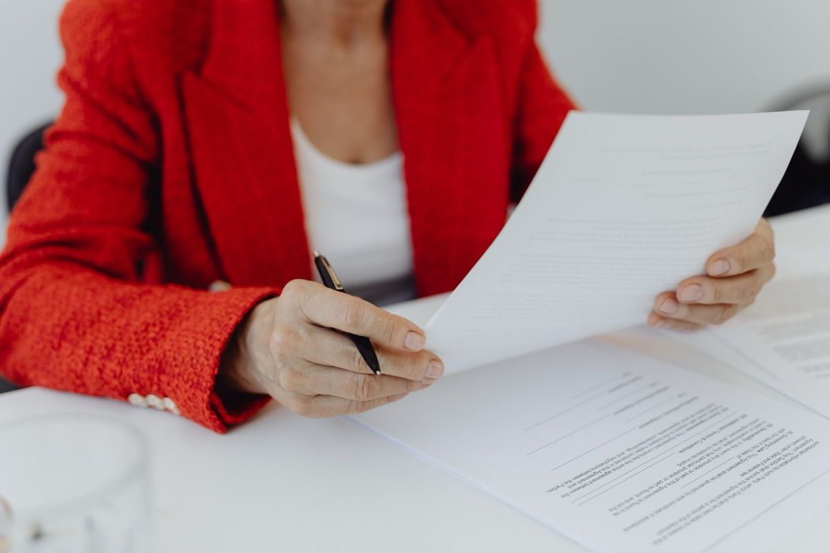 Person in a red jacket holding and reviewing documents at a desk