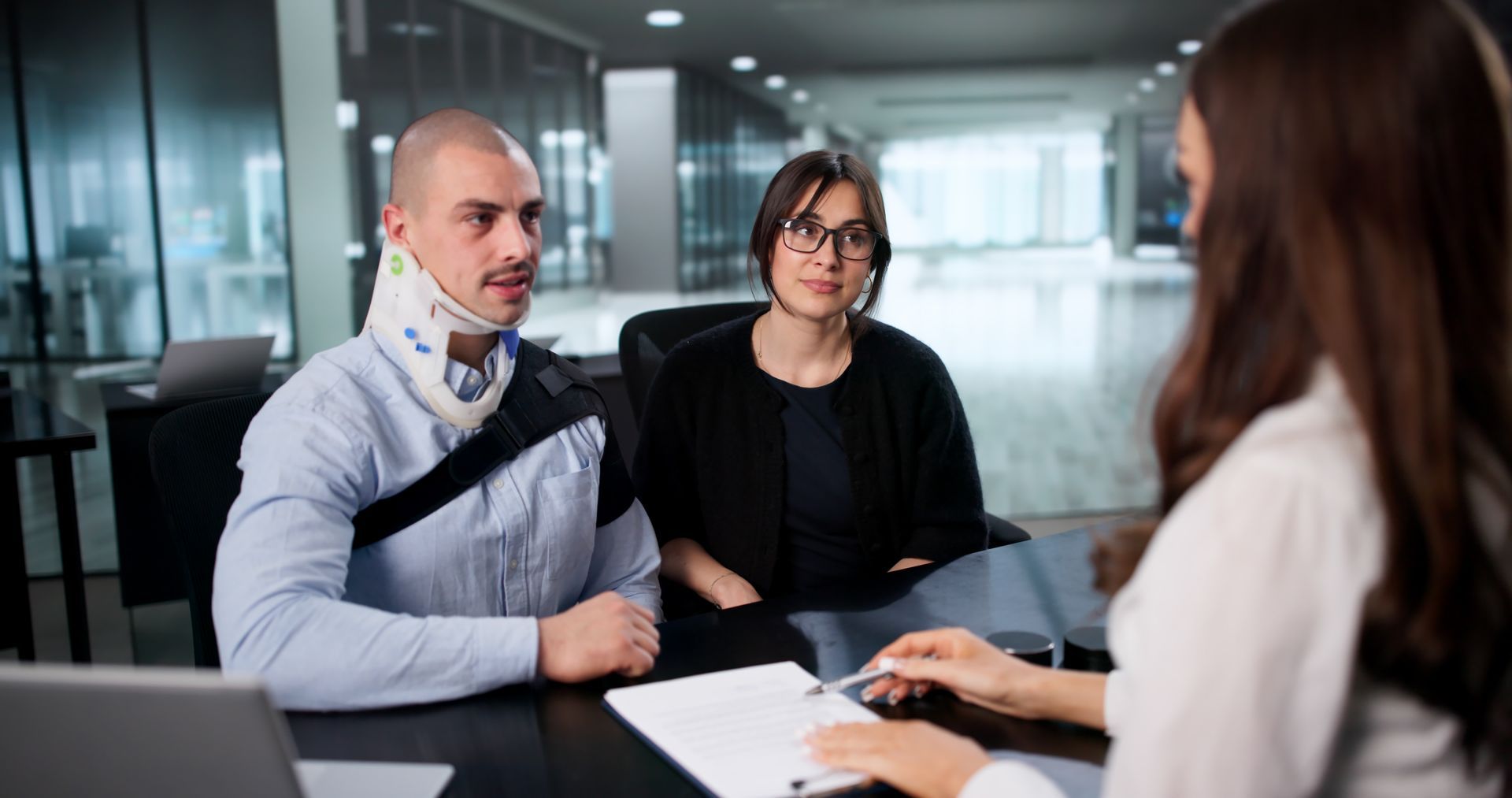 Injured client in neck brace and sling meeting personal injury attorney. Injured client in neck brace and sling meeting personal injury attorney.