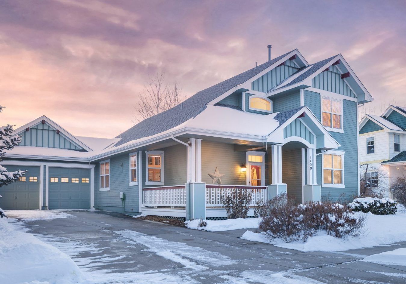 A blue house with a garage is covered in snow.