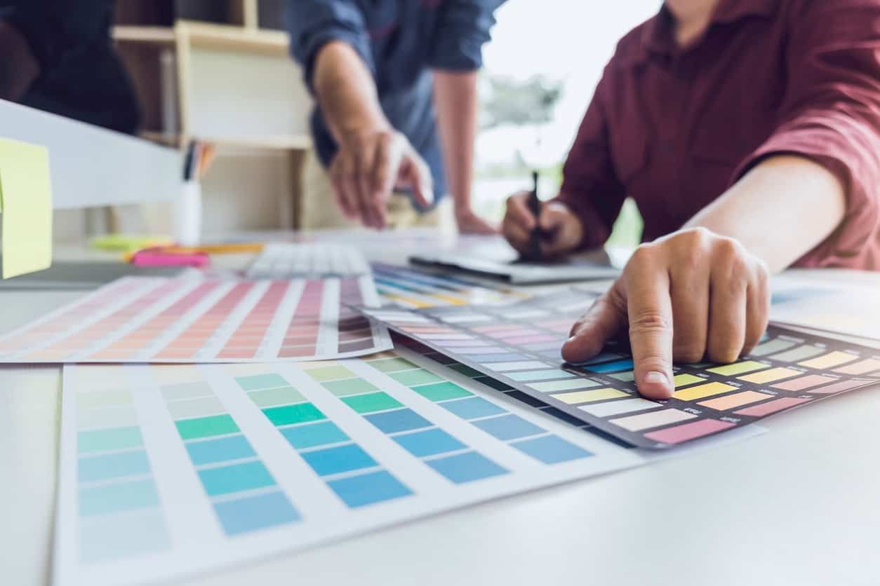 A group of people are sitting at a table looking at color samples.
