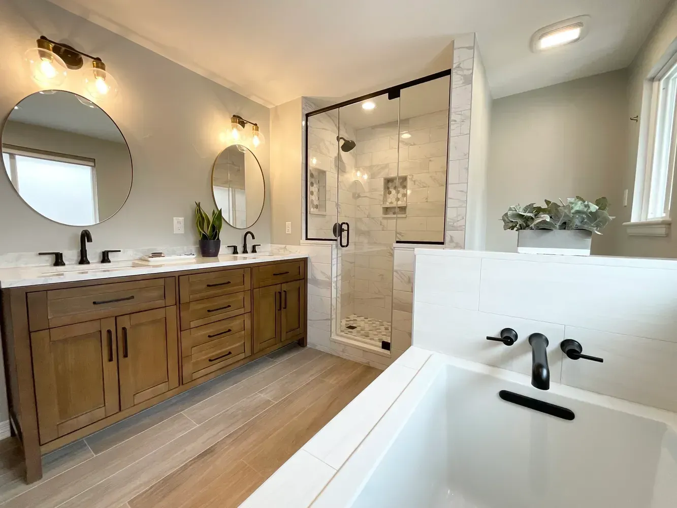 A bathroom with two sinks , a tub , and a shower.