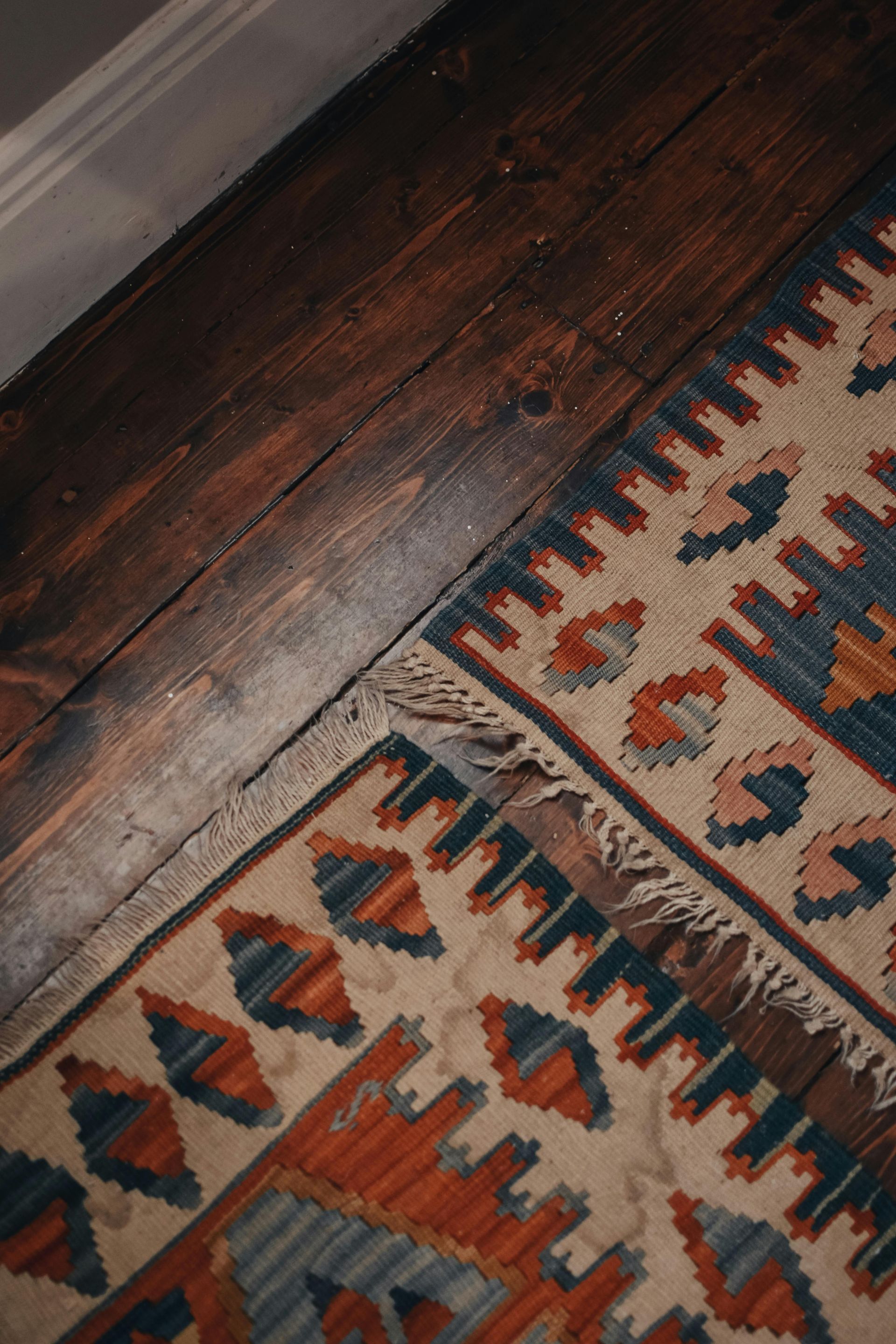 A rug is sitting on a wooden floor next to a wall.
