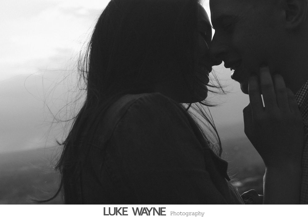 Couple touching noses, silhouetted against a bright background; romantic moment.