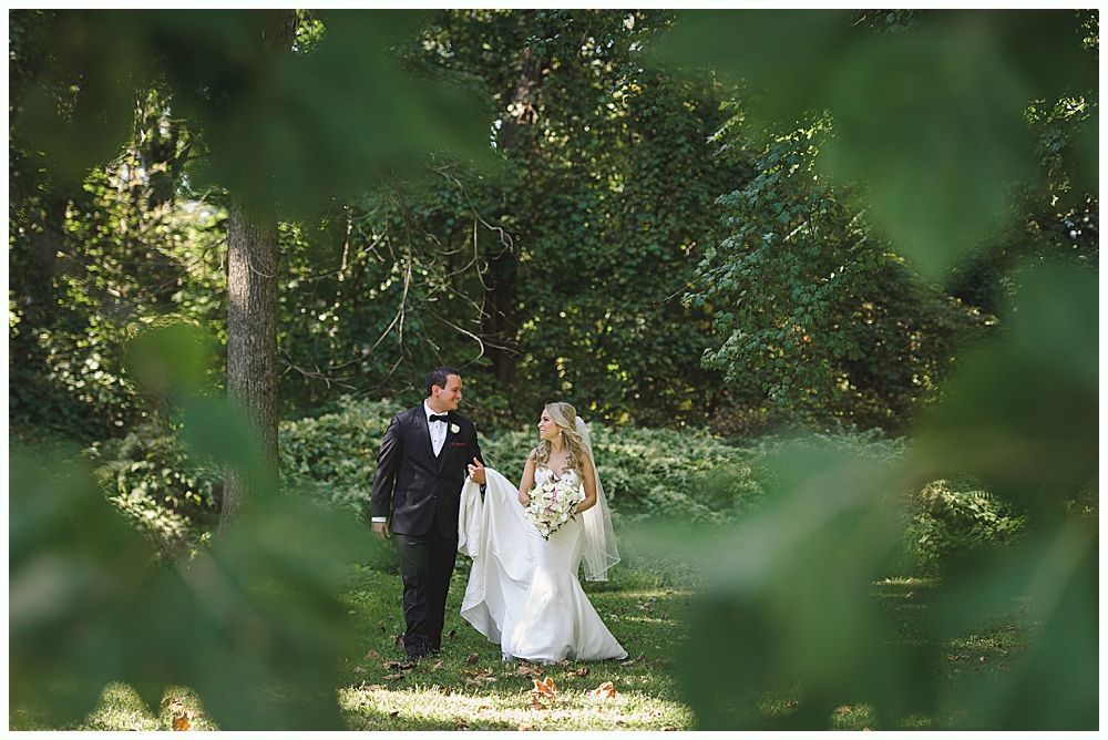 Wooden wedding arch decorated with greenery and red and white flowers, outdoors.