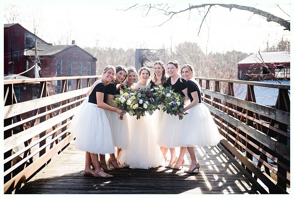 Newlyweds exiting outdoor wedding ceremony, holding hands, smiling. Wedding party applauds.