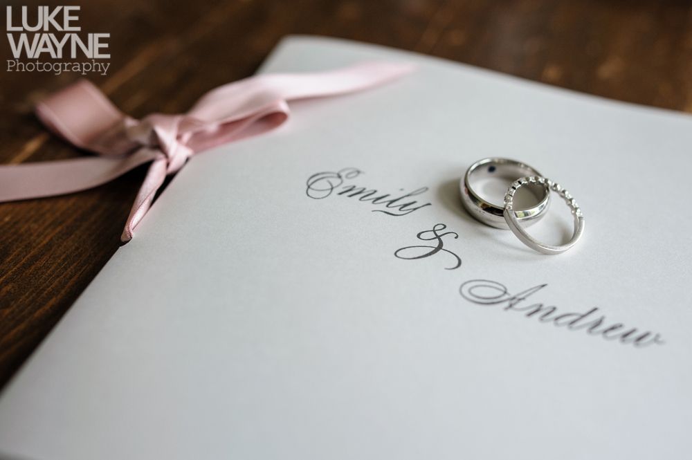 Wedding rings on a program tied with a pink ribbon; names 